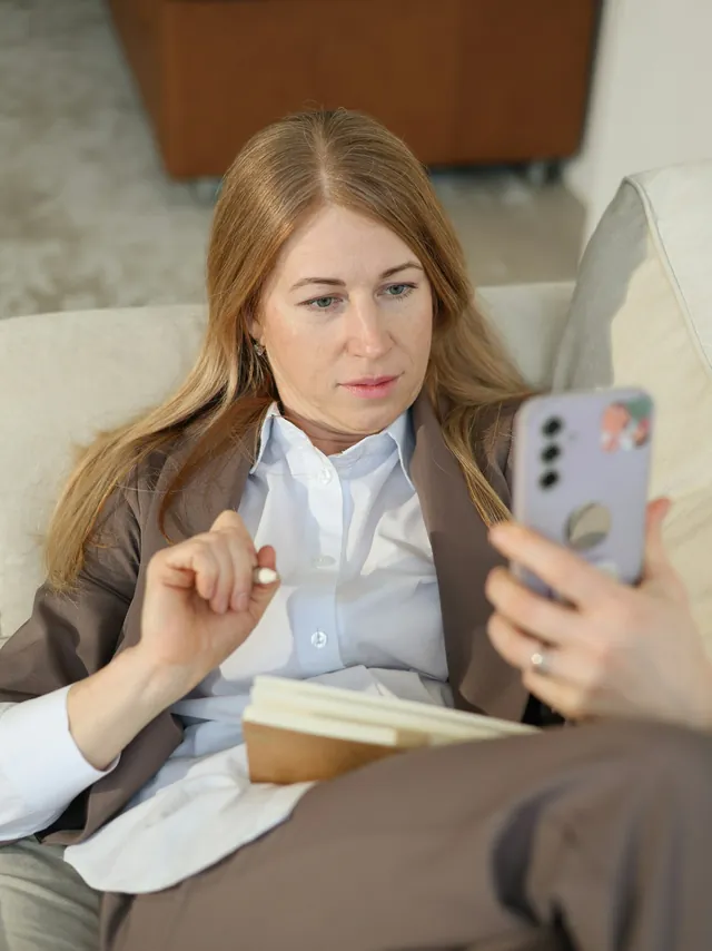 Someone reading study information on a phone, with a notebook open beside them